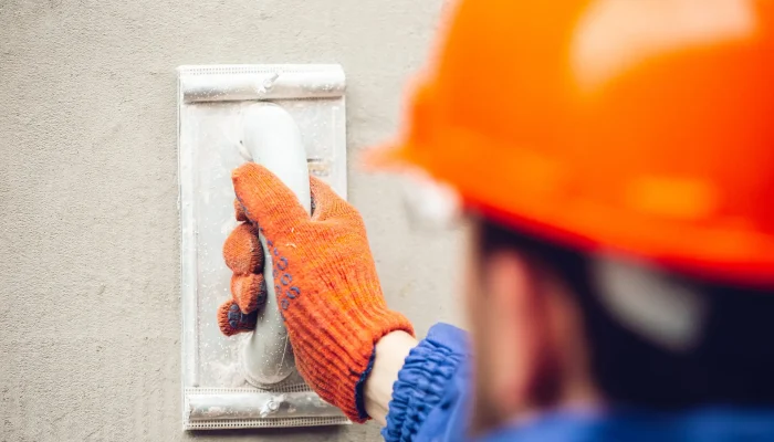 Closeup of repairman in uniform, professional builder working using construction equipment. Process of building, apartment renovation, repairing, building. Coloring, measuring, preparing the base.